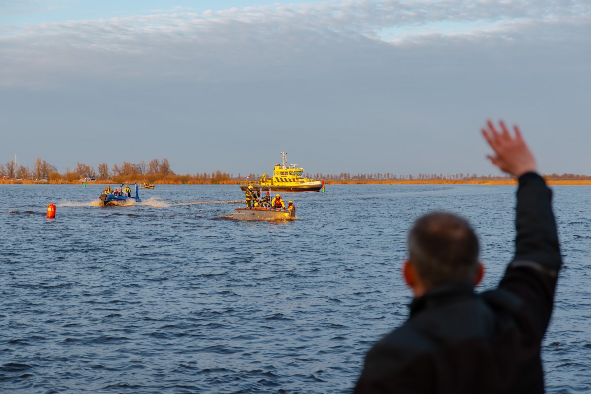 Man zwaait naar de boten van de hulpdiensten.