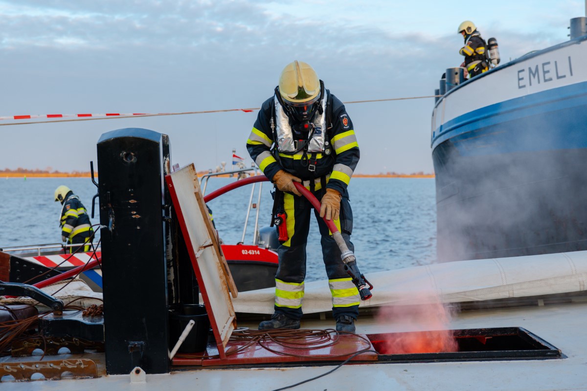 Een brandweerman blust de brand in het skûtsje.